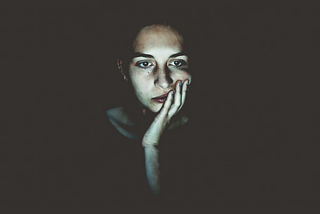 Woman sitting in the dark lit by a screen