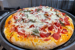 A large homemade pizza with tomatoes, mozarella cheese, and rosemary