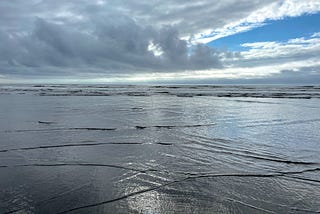 A silver sea with a blue streak of sky between clouds