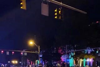 a screenshot from June 24, 2020, shows CPD in riot gear and in formation in front of the Ohio Statehouse, lit up in rainbow colors for Pride Month. Text at the top of the photo reads: broadcast interrupted.
