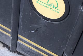 The gypsy walks out of Leyton tube station and spits. He misses the ground and hits the bin.