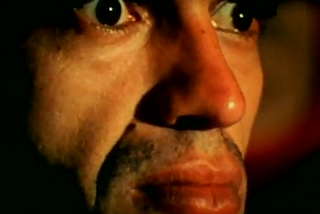 O ator José Dumont com olhos arregalados e fixos assistindo a um vídeo em cena de O Homem que virou suco