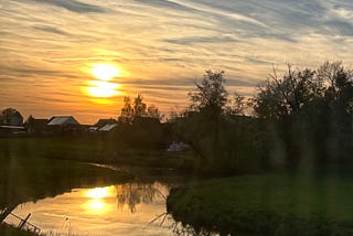 A sunset view with houses and trees and a river