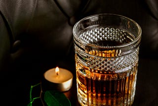 A glass of whisky and a lit candle