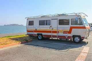 Old RV in a parking lot; alt-text for “I Had the Best Night’s Sleep in a Cracker Barrel Parking Lot”