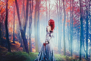 A woman walking through the woods wearing a long pretty dress