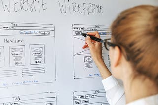 Content designer working on a whiteboard creating a website wireframe