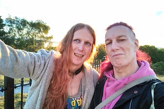 two people outside in the sun, smiling for a selfie