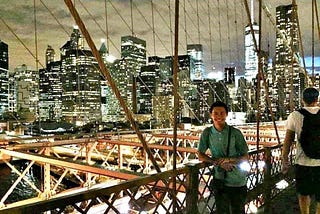 a man standing on a bridge with the city of New York in the background