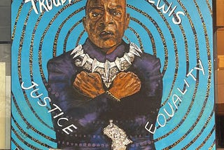a large mural painting of John Lewis as Black Panther crossing his arms in a “Wakanda Forever” sign. With words that say Justice and Equality