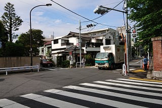 Beyond a zebra crossing on a wide road, the beginnings of an old Tokyo neighbourhood