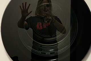 A selfie of me taken in the reflection of a dryer door. I’m trying to recreate the classic Boy Behind Glass stock image for autism