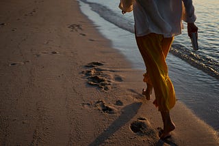 Back view of a woman walking on the beach.