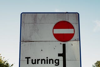 Street sign indicating that the route ahead is blocked and vehicles must take a turn.