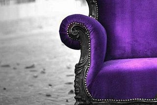A comfortable, antique purple armchair placed on a cobbled old road.