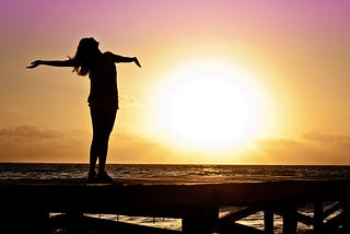 image of woman on beach greeting the sun