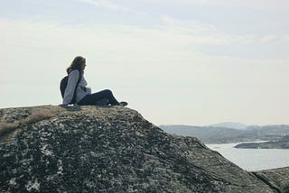 the author sits on a high rock looking over the baltic see