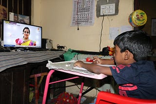 A kid looks at the TV playing a video lesson on the KITE VICTERS channel