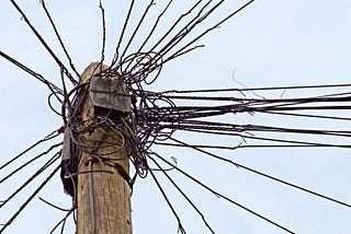 A nest of confusing wires on a telephone pole.