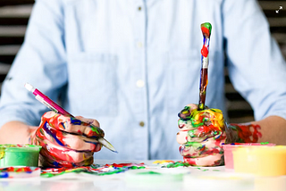 a person’s hands all tainted with paints