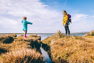 Mother and daughter separated by a narrow creek