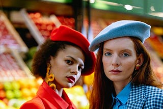 two girls, one wears a red beret and the other a blue one