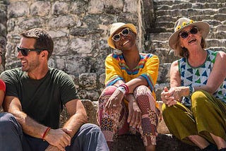 5 people sitting on stone steps, smiling at the camera and each other