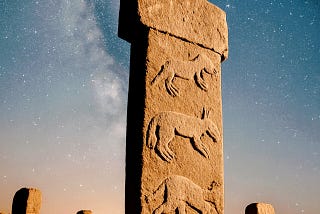 A carved prehistoric stone pillar standing upright under a star-filled night sky, inspired by Göbekli Tepe.
