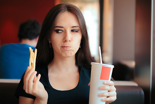 Hesitating woman thinking about eating fast food or not