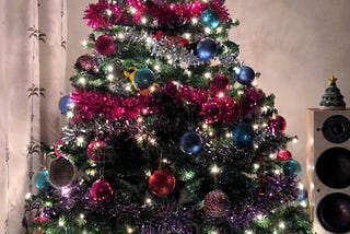 A decorated christmas tree with baubles and tinsel lit up by tiny lights in the tree