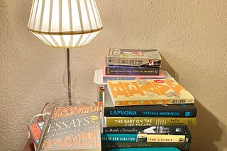 A photo of books stacked on my bedside table