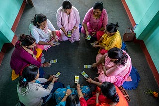 A group of women holding smartphones sit in a circle.