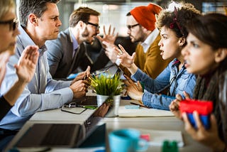 People sitting at a table arguing with each other — they look angry.