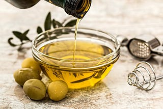 Bowl of olive oil being filled by bottle