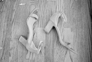 A pair of heels lie on a hardwood floor