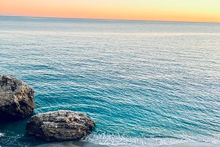 Sunset on the beach with rocks on the coast of Spain. Pretty blue and orange colors.