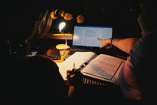 A student studies late at night, surrounded by notes and a laptop, illustrating academic pressure and exhaustion