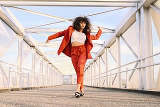 A Black woman in a red suit dancing across a bridge. trump, news, Black peopel