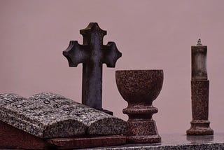 A photo of a gravestone formed to look like an open book with a cross and goblet.