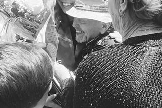 Black and white image of a laughing young woman, graduating, being hugged by family, Carly Newberg, Medium