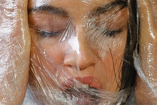 A woman wrapped in plastic, suffocating.