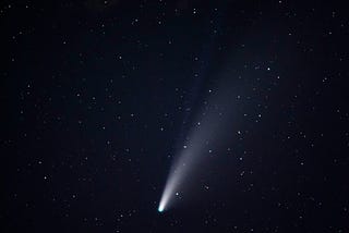 A comet with two tails is passing in the night sky