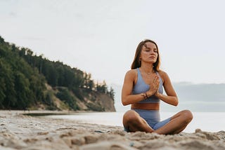 Girl meditating in yoga outfit on beach