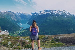Woman stands at edge of mountain overlooking river in Norway