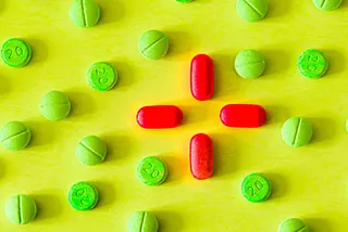 An array of green and red pills against a yellow background.