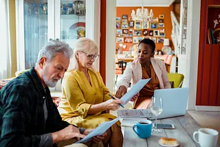 Three people sitting at a table looking at papers.