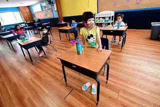 Children in a pre-school class wear masks and sit at desks spaced apart as per coronavirus guidelines during summer school.