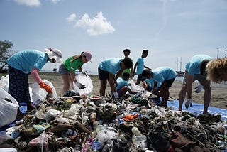 Group collecting trash from large pile on a beach