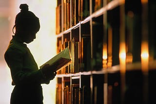 Young Black girl reads a book in school library.