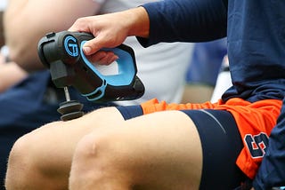 A Syracuse Orange player uses a TheraGun during warm ups prior to the game against the Connecticut Huskies.